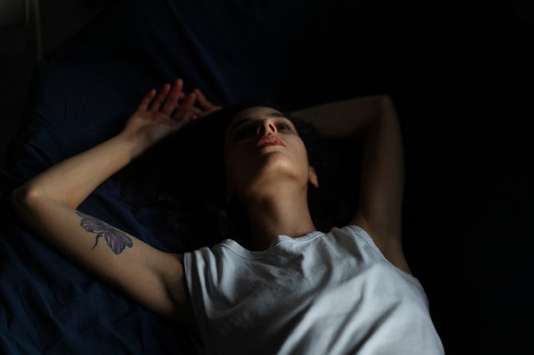 A woman with headache lying with a worrisome facial expression