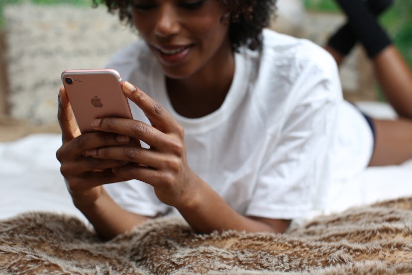 A girl smiling while texting on her mobile phone