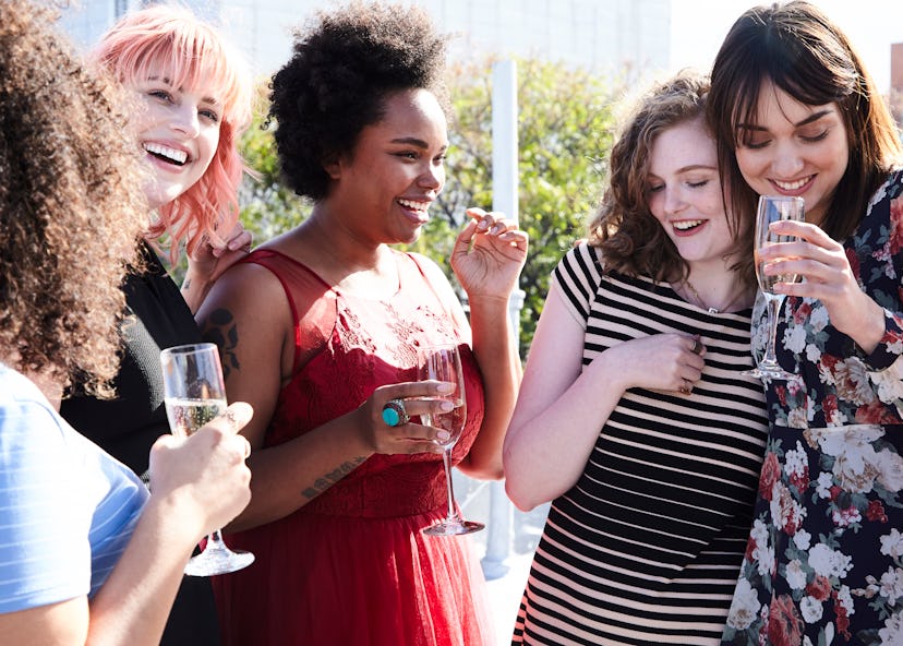 Five female friends laughing and having fun while drinking champagne