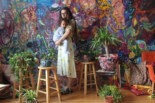 Millennial mom holding her baby in a room full of house plants