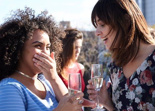Two women share drinks on a rooftop. Doctors explain subtle symptoms of alcohol intolerance.