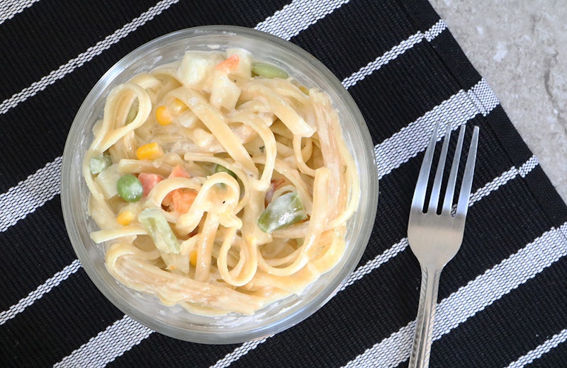 An easy fettuccine alfredo dish in a bowl on a striped tablecloth 