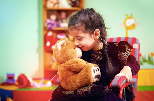 A kid with Autism playing with her teddy bear toy