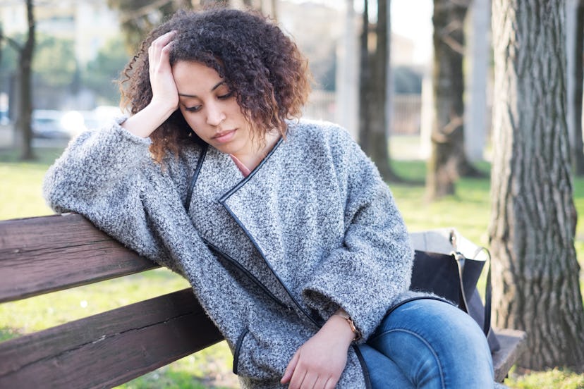 A sad woman sitting on a street bench