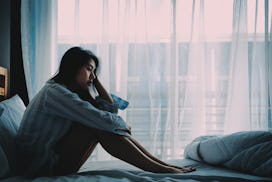 Young woman sitting on her bed sadly because of feeling lonely