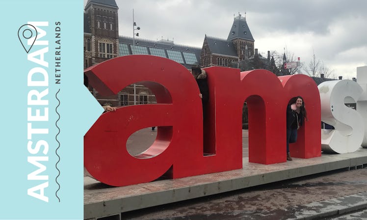 A girl peeking trough the Amsterdam sign in the Netherlands. 