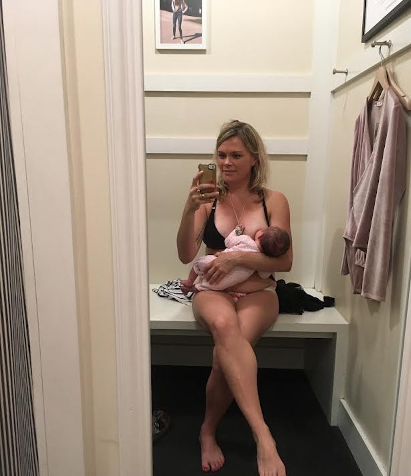 A mother taking a mirror selfie while breastfeeding her baby