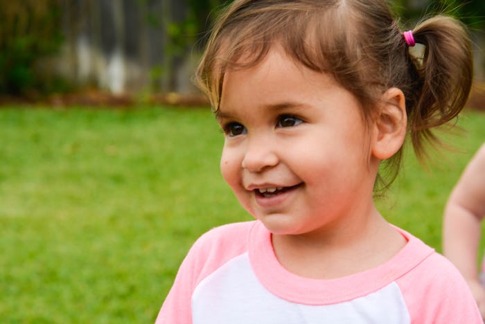 A 2-year-old girl with pig tails in a pink and white shirt