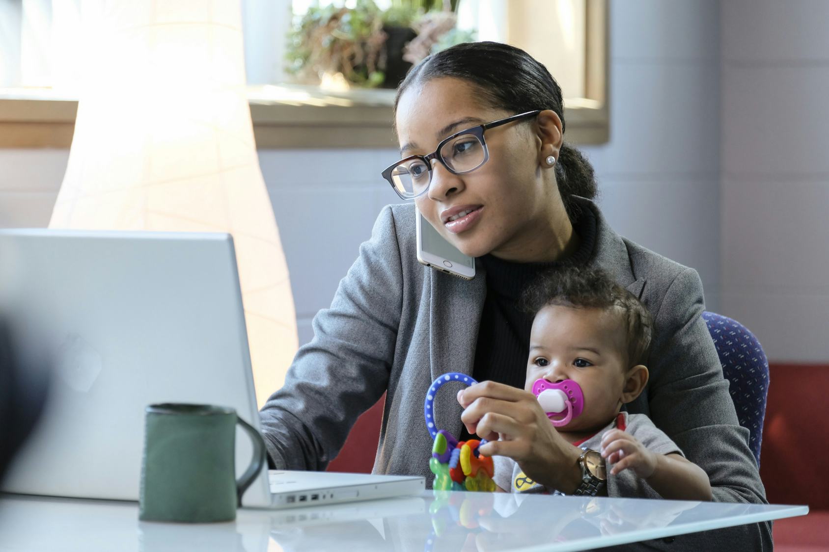A mom working on her laptop while her baby is sitting on her lap