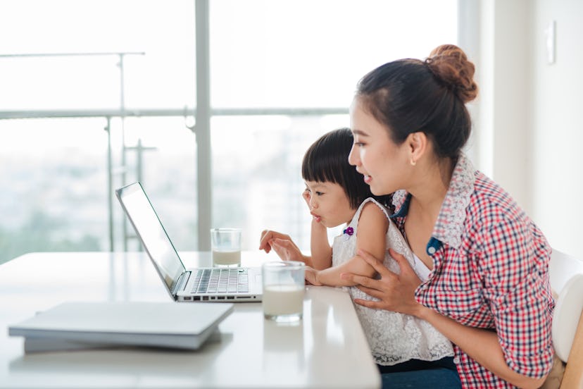 A mom showing her daughter what she does for work on laptop