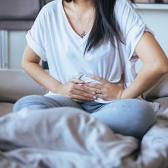 A woman holding her stomach because of pain caused by PCOS