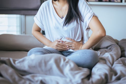 A woman holding her stomach because of pain caused by PCOS