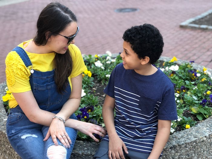 A woman feeling mom burnout talking to her child while sitting in a park.