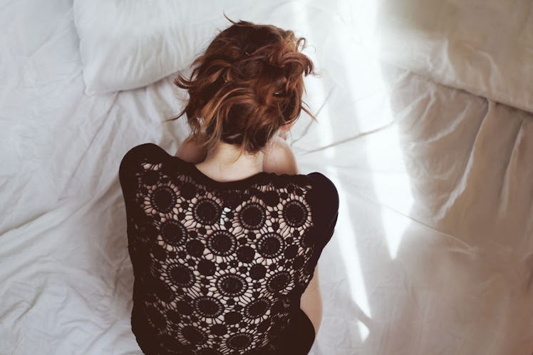 A woman struggling with PCOS curled up in bed
