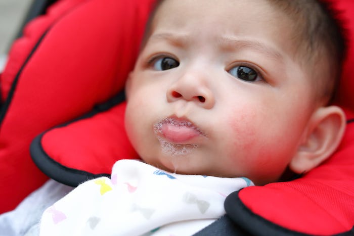 A baby drooling while sitting in a car seat