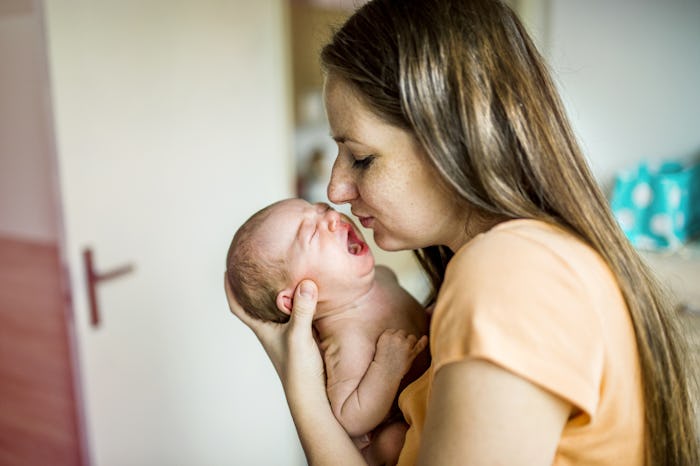 A mom who feels like a new person after having her baby, holding her newborn near her face