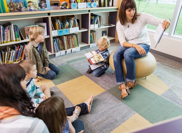 A teacher in a classroom with kid reading from a book, and one boy is language delayed