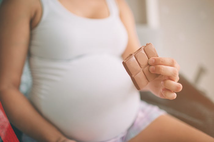 Pregnant woman in her undershirt eating milk chocolate