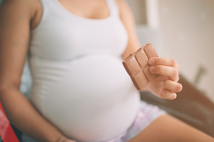 Pregnant woman in her undershirt eating milk chocolate