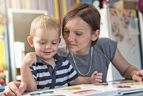 A boy and a preschool teacher reading a book together
