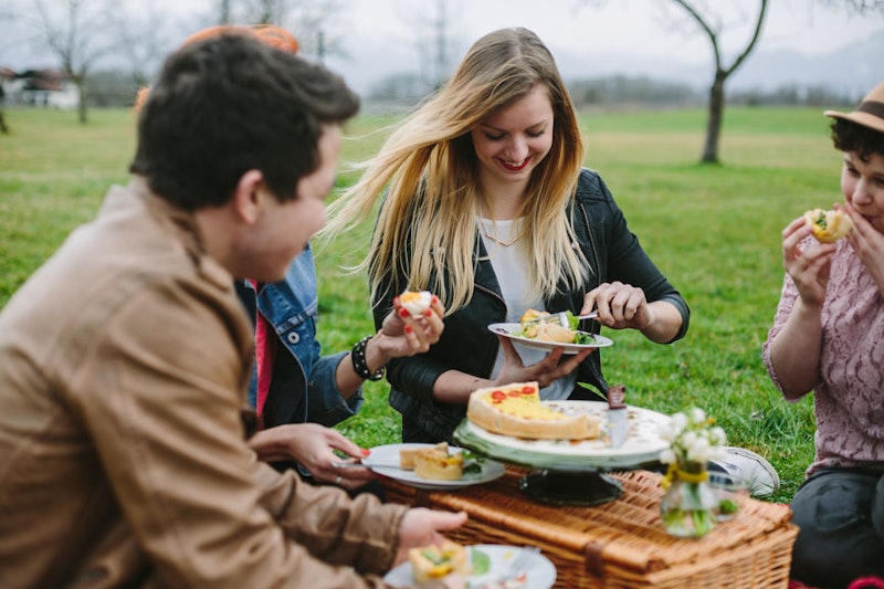 Four friends eating vegan BBQ food on a picnic