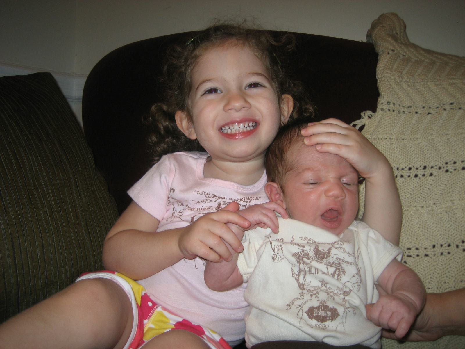 A toddler sister hugging her baby brother