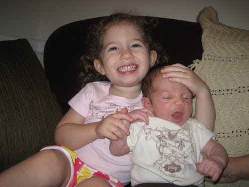 A toddler sister hugging her baby brother