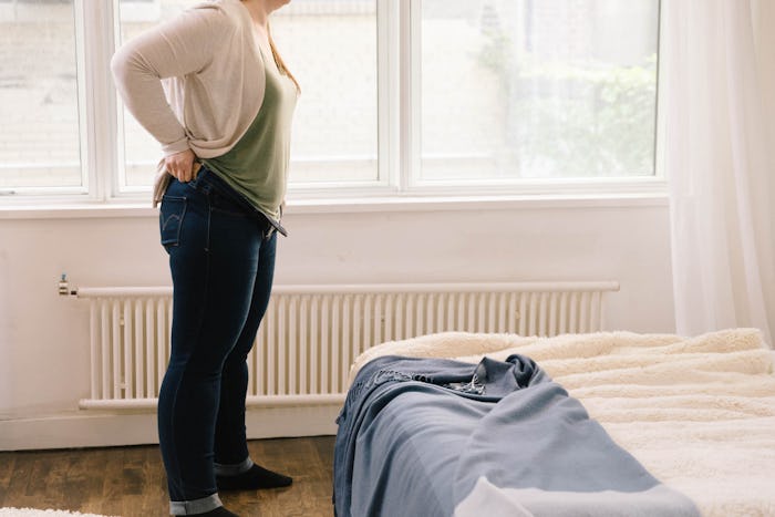 Woman standing in her bedroom feeling bloated because of ovulation
