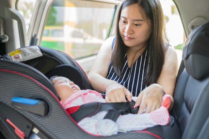 An Asian mom buckling up her baby in the baby seat