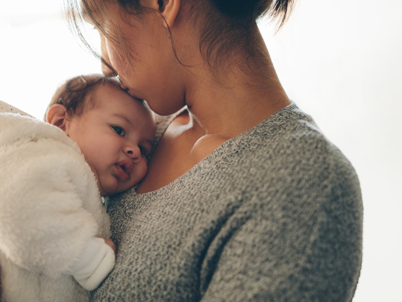 A mom holding and kissing her baby