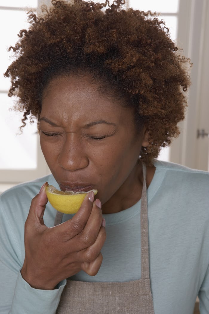 A pregnant woman indulging her super sour pregnancy craving by sucking on a lemon