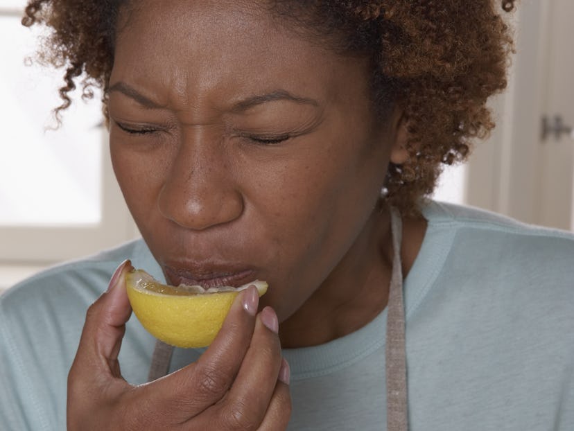 A pregnant woman indulging her super sour pregnancy craving by sucking on a lemon