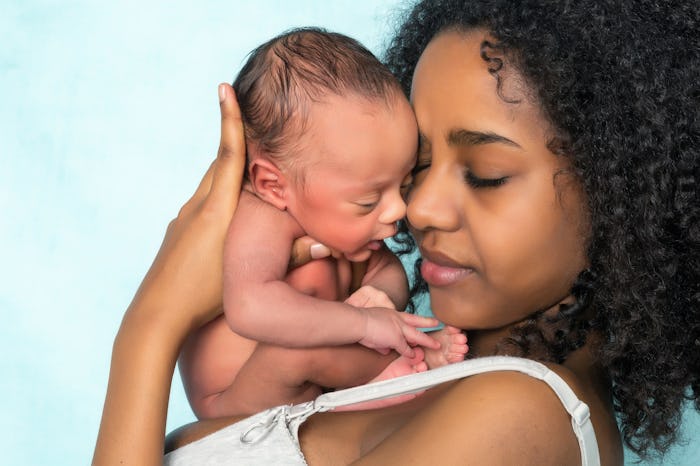 Young woman holding her newborn baby on her chest.