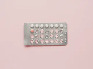 A pack of birth control pills on a pale pink surface