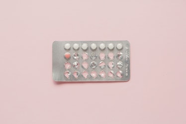 A pack of birth control pills on a pale pink surface