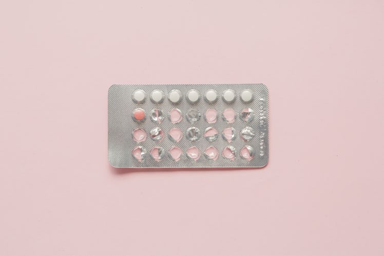 A pack of birth control pills on a pale pink surface