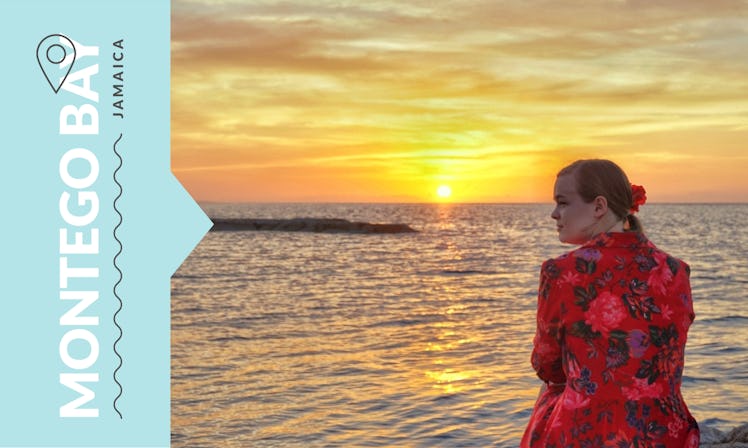 Katie Lockhart in a red floral dress, sitting on a shore in Montego Bay, Jamaica.