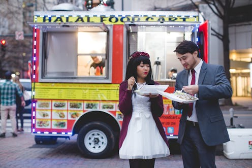 Bianca and Carsie eating happily in front of their favorite halal cart on their wedding day