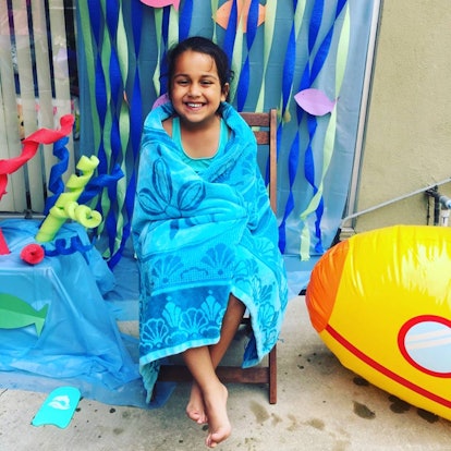 Little girl covered with a blue towel after taking a swim in the pool
