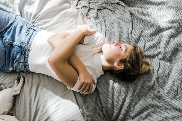 A woman lying in her bed holding her chest.