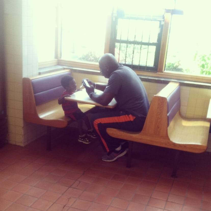 A father sitting at a restaurant table and using his phone