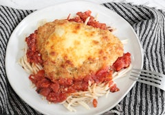Chicken parm served with a fork on a plate that has a blanket beneath