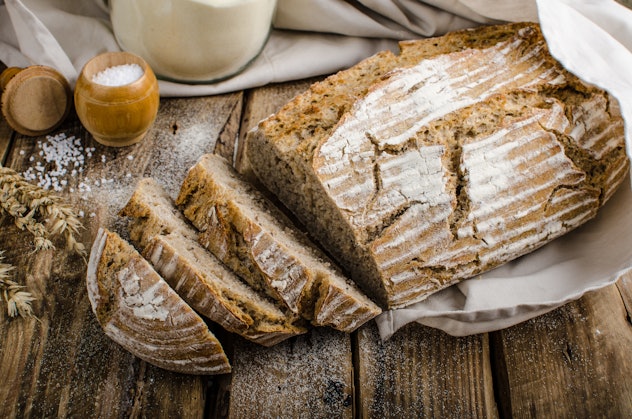 Sourdough Bread sliced with salt and butter next to it, all sitting on wooden planks