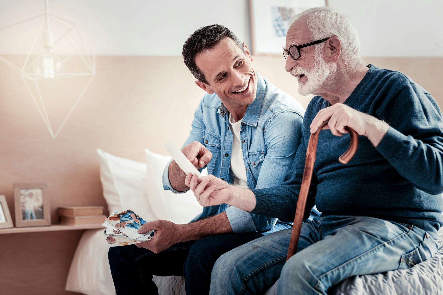 A man sitting with his father on the bed looking through old photos.