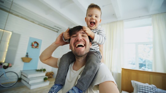 A dad laughing while carring his son on his shoulders through the house taking a selfie