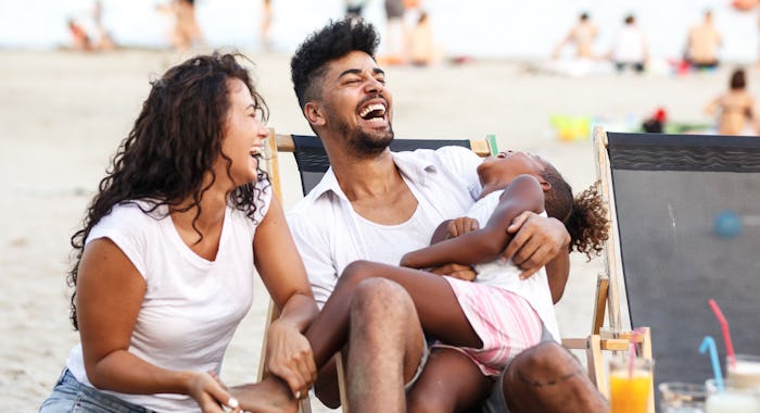 mom dad daughter laughing at beach