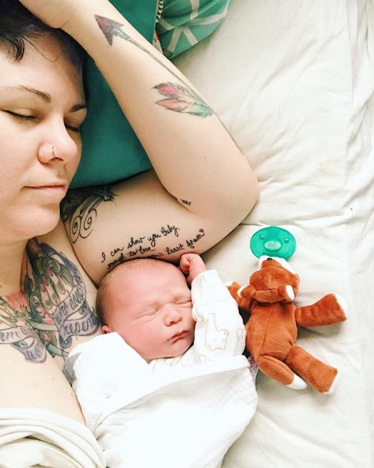 Tattooed woman and her baby sleeping in the bed with her child's favorite toy
