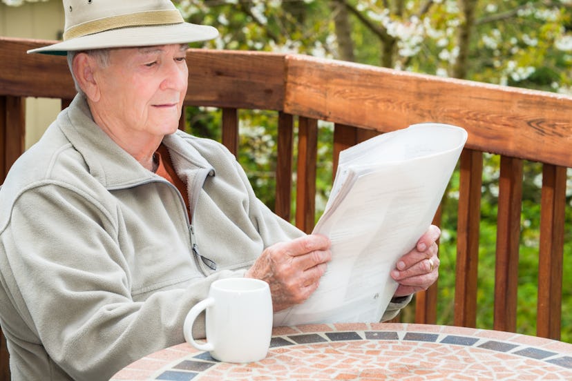 Old Grandpa sitting on the front porch reading newspapers