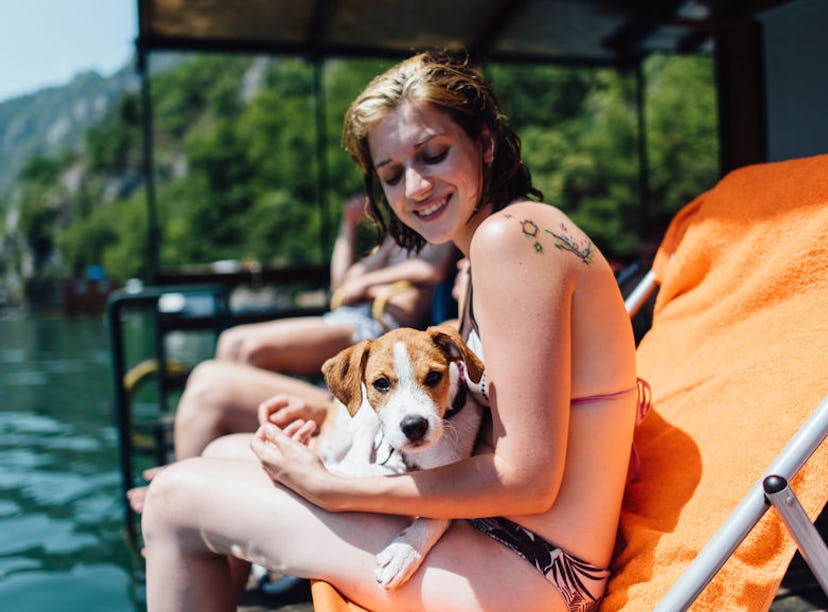 Young woman holding her dog at her friend's lake house, in need of lake Instagram captions.