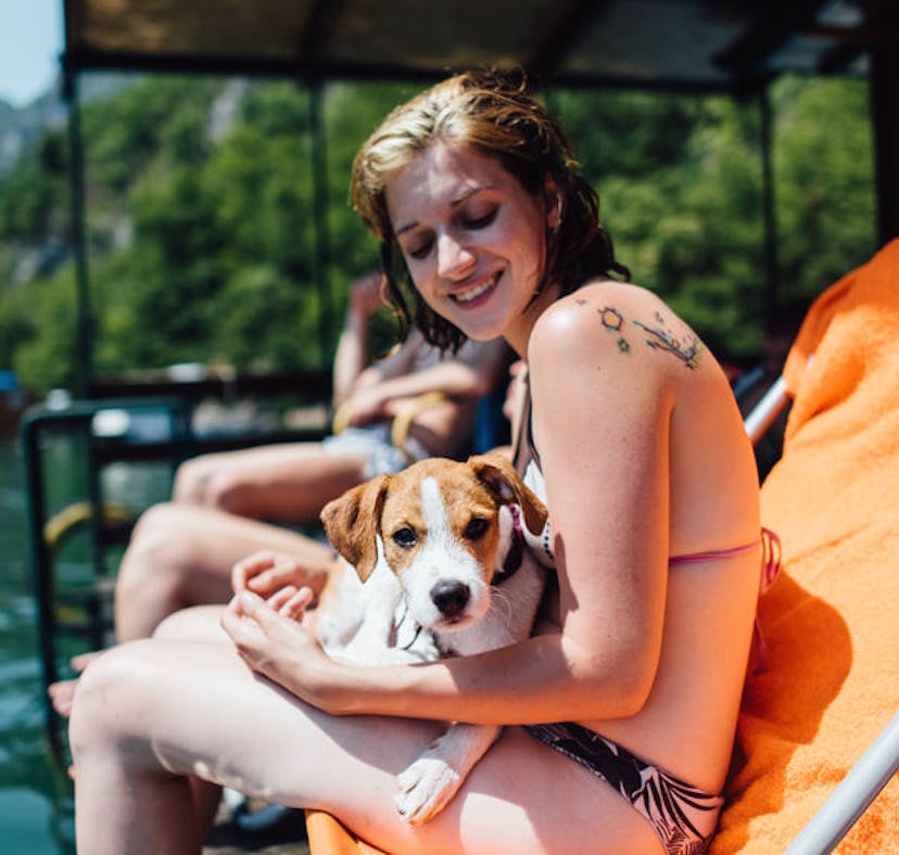 Young woman holding her dog at her friend's lake house, in need of lake Instagram captions.
